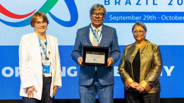 A plaque of appreciation is presented to Elias Ramos de Souza (centre), of FINEP. (Photo: Mario Marques)
